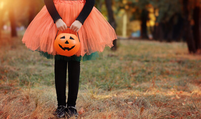 Little girl in witch costume with a pumpkin bucket . Kid having fun at Halloween trick or treat....