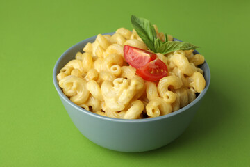 Plate with macaroni and cheese on green background