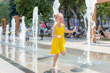 a little happy girl runs near the fountain in the summer in the park