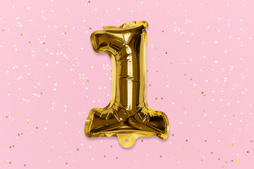 The number of the balloon made of golden foil, the number one on a pink background with sequins. Birthday greeting card with inscription 1. Top view. Numerical digit, Celebration event, template.
