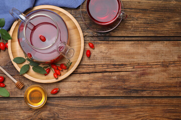Flat lay composition with aromatic rose hip tea on wooden table. Space for text