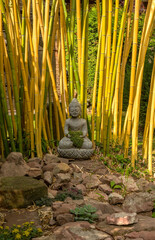 Buddha sculpture made of stone in front of a bamboo in the garden
