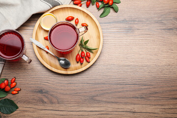 Fresh rose hip tea, honey and berries on wooden table, flat lay. Space for text