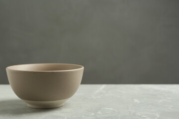 Stylish empty ceramic bowl on grey table, space for text. Cooking utensil