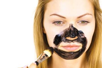 Girl being apply black mask to skin face