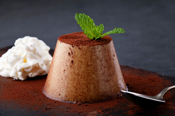 Close up of coffee panna cotta with cocoa and cream on black background