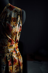 a bright handmade summer dress on a mannequin. a fashion designer makes a sundress of individual tailoring. fabric with a pattern of flowers. photo of clothes on a mannequin on a dark background