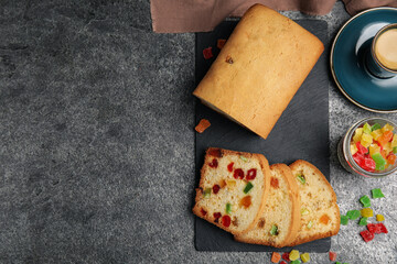 Delicious cake with candied fruits and coffee on grey table, flat lay. Space for text