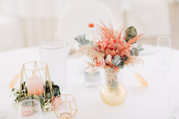 table setting for a party. Dry flowers in a vase next to a candle. Table decorations for a wedding in boho style. Wedding decoration in earth tones 