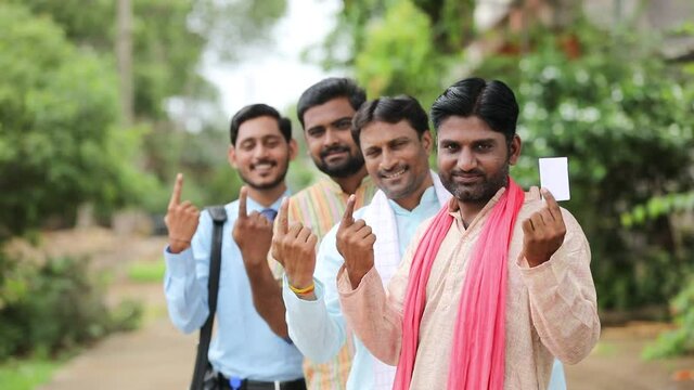 Young Indian farmers showing finger after voting with officers.