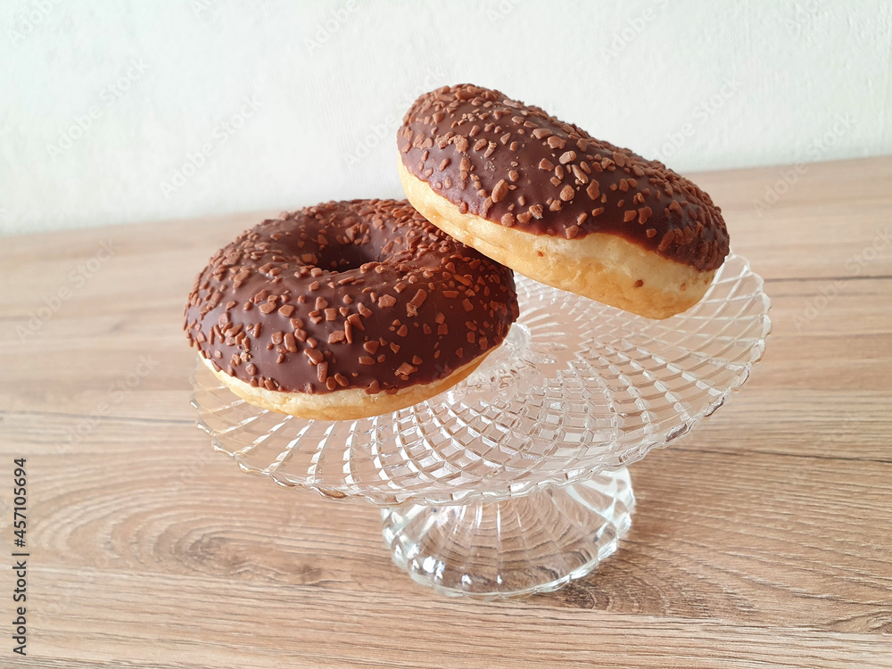 Wall mural Closeup shot of chocolate doughnuts on a glass plate container