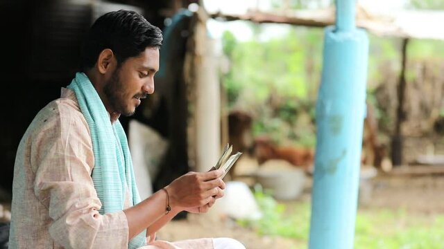 Happy Indian farmer counting money at home.