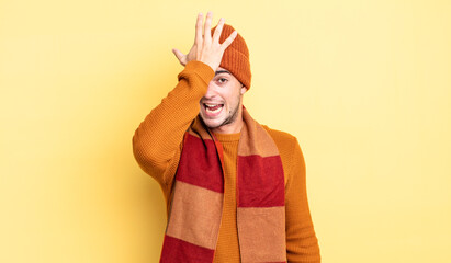 young handsome man raising palm to forehead thinking oops, after making a stupid mistake or...