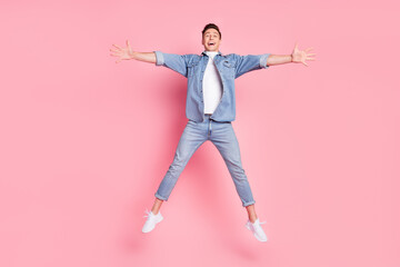 Fototapeta na wymiar Full size photo of young good mood cheerful guy jumping with open hands isolated on pink color background