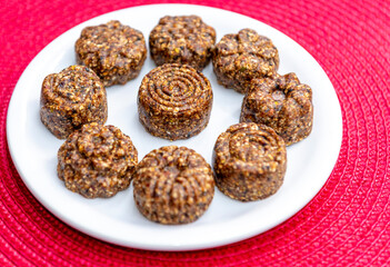 Raw vegan brown cookies on white plate and red background. less sugar consumption.