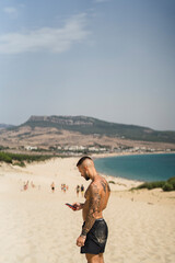 Fototapeta na wymiar Chico atletico tatuado posando en dunas de arena
