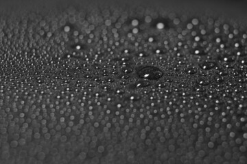 Macro of water drops with reflections on a glossy black surface
