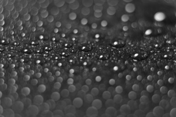 Macro of water drops with reflections on a glossy black surface