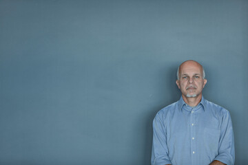 Serious thoughtful man standing in front of a blank chalkboard
