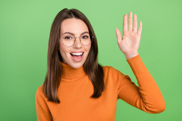 Portrait of attractive cheerful brown-haired friendly girl waving you hi hello greetings isolated over green color background © deagreez