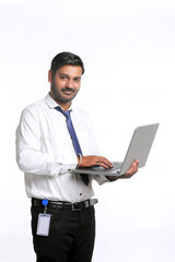 Naklejka na ściany i meble Young indian man using laptop on white background.