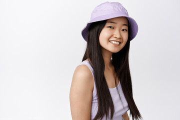 Close up portrait of brunette asian girl smiling, looking happy at camera, standing in stylish summer outfit against white background