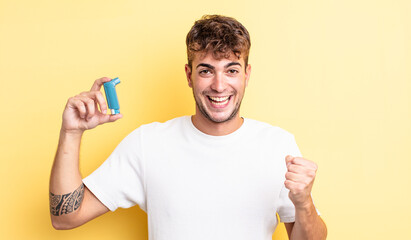 young handsome man feeling shocked,laughing and celebrating success. asthma concept