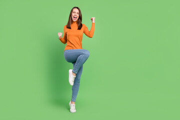 Full length body size photo girl in orange turtleneck gesturing like winner isolated pastel green color background