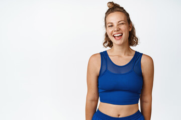 Fototapeta na wymiar Portrait of happy sports woman winking, smiling and looking at camera, wearing blue activewear for fitness workout, white background