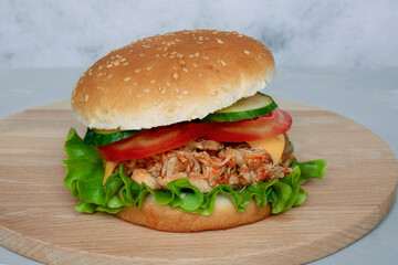 Pulled Chicken, Pork with lettuce, cucumber and tomato on a wooden board light background