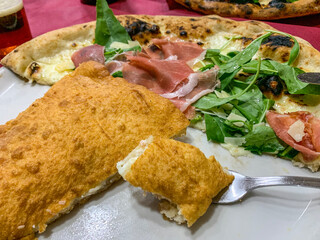 Piatto con pizza fritta napoletana ripiena di ricotta e pancetta e pizza napoletana con prosciutto crudo, rucola, formaggio e mozzarella di bufala 