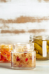 Fototapeta na wymiar Sauerkraut, kimchi, and pickles in mason jars, canned food on a rustic wooden background with a place for text