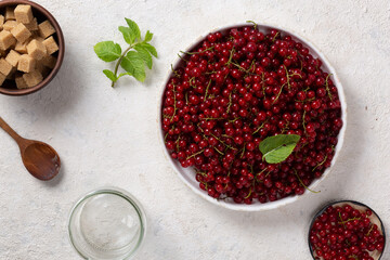 Red currants in a white dish on a light table, healthy food, diet