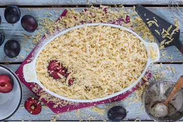 Grated pie with plums is prepared in the home kitchen, top view