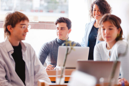 Young woman with facemask working on her laptop at the office