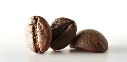 Macro of three coffee beans on white table front
