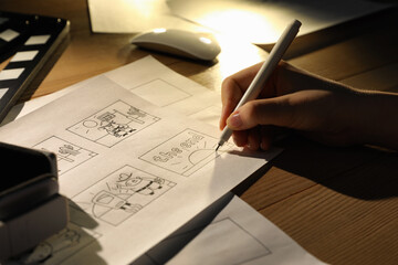 Woman drawing cartoon sketches at workplace, closeup. Pre-production process