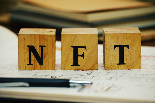Selective focus on text NFT on wood cube block decorate on the artist sktch book , new digital market concept.