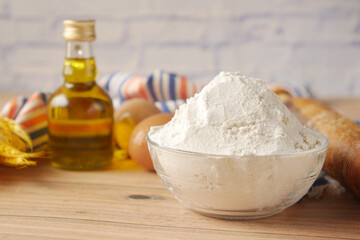wheat flour in a bowl , egg and oil on table 