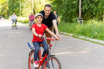 happy family father teaches child daughter to ride a bike in the Park in nature