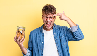 young handsome man looking unhappy and stressed, suicide gesture making gun sign. cookies bottle...