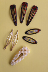 Tortoise shell sunglasses and various hair accessories on yellow background. Flat lay.