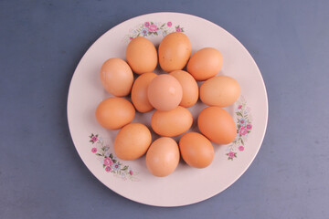 Randomly stacked pile of raw chicken eggs on a white plate