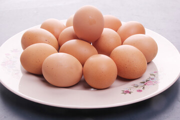 Randomly stacked pile of raw chicken eggs on a white plate