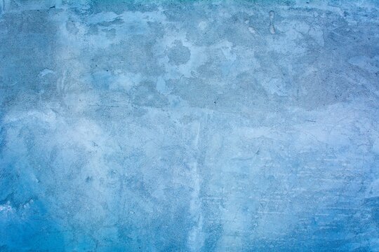 Old blue wall in spots, cracks, stains. Painted concrete wall in abstract grunge style loft. Vintage wall background texture for backgrounds, portraits, posters.