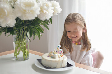 A girl of 4 years old making wish blowing candles on a cake