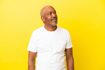 Cuban Senior isolated on yellow background looking to the side and smiling