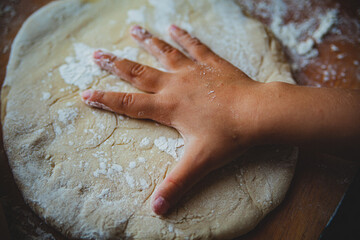 raw wheat dough on a wooden kitchen board in flour