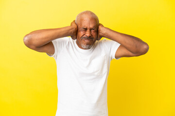 Cuban Senior isolated on yellow background frustrated and covering ears