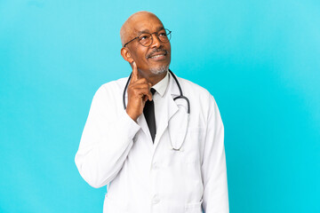 Senior doctor man isolated on blue background thinking an idea while looking up